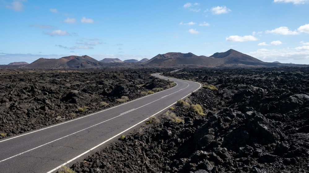 Strada tortuosa tra colate di lava nera verso i vulcani di Timanfaya