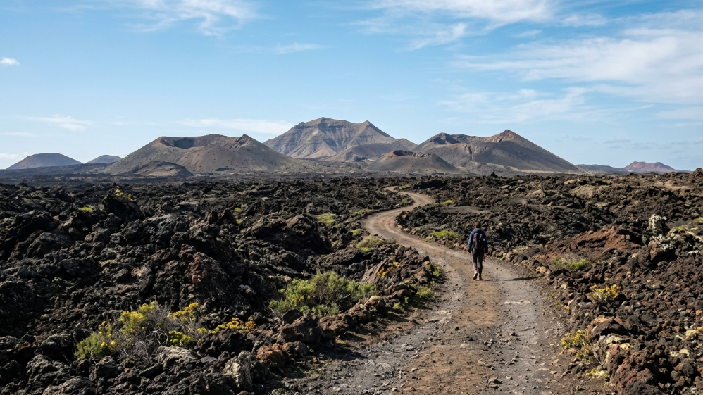Escursionista cammina tra le colate laviche verso i vulcani di Timanfaya