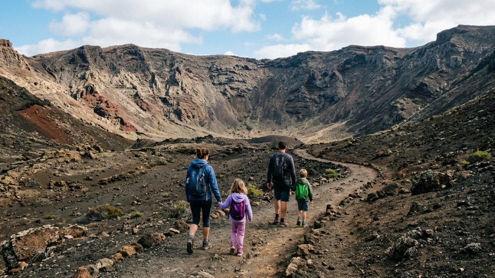 Familia con niños caminando por un sendero hacia un cráter volcánico