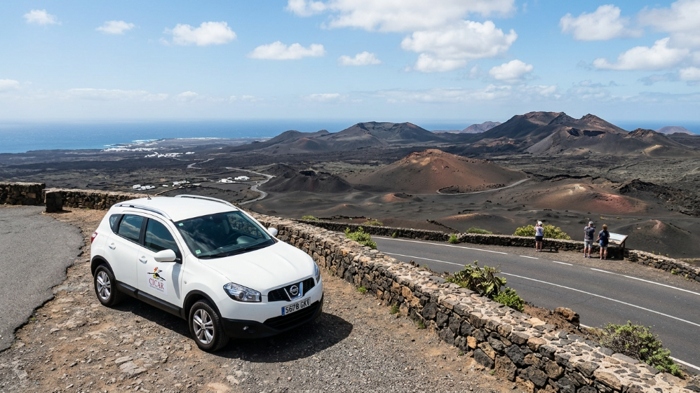 Auto a noleggio bianca in un belvedere con vista sui vulcani del Parco Nazionale di Timanfaya