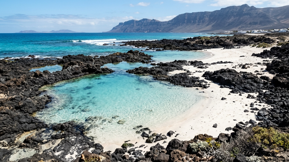 Turquoise natural pool surrounded by volcanic rocks near Famara beach
