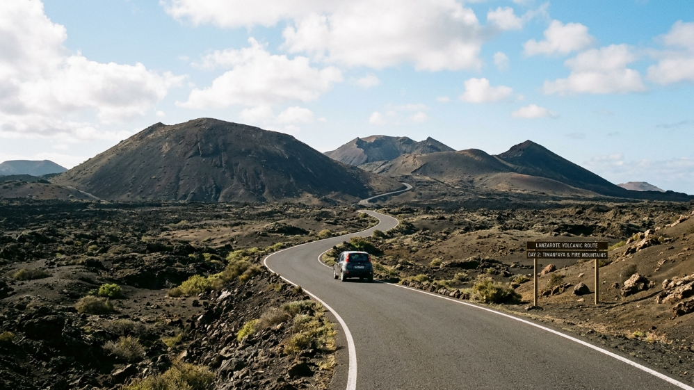Car driving along a winding road between volcanoes in Timanfaya