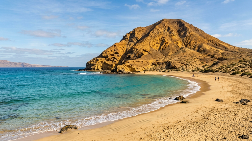 Playa de arena dorada junto a montaña volcánica en La Graciosa